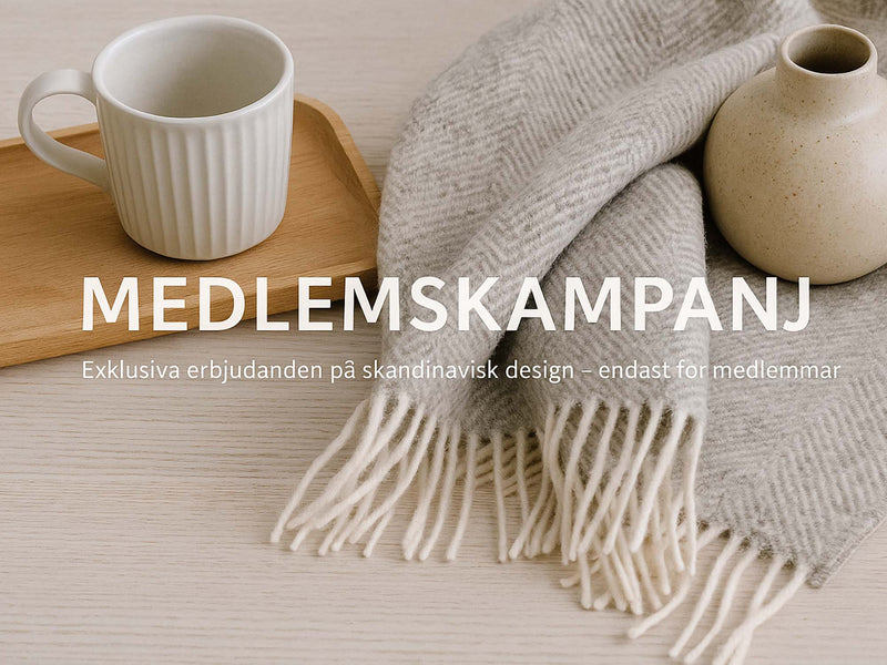 Bilden visar en varm och scen i skandinavisk stil: en ljus träyta med en vit kopp, en mjuk grå filt och en beige vas. I mitten står texten MEDLEMSKAMPANJ med undertiteln Exklusiva erbjudanden på skandinavisk design, endast för medlemmar